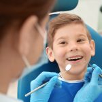 Dentist examining little boy's teeth in clinic