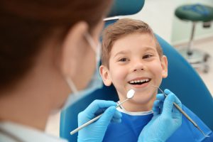 Dentist examining little boy's teeth in clinic