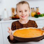 happy little child holding baking tray with thanksgiving pie