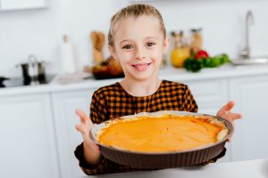 happy little child holding baking tray with thanksgiving pie