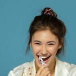 Happy funny teen girl brush her teeth, healthy concept. Morning theme, over blue background.