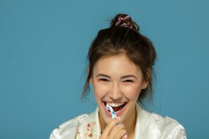 Happy funny teen girl brush her teeth, healthy concept. Morning theme, over blue background.