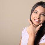 Young woman with healthy teeth on color background. Space for text