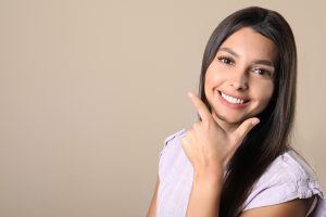 Young woman with healthy teeth on color background. Space for text