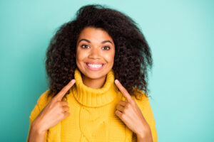 Closeup photo of amazing dark skin curly lady indicating fingers on perfect, teeth advising dentist wear yellow knitted pullover isolated blue teal color background