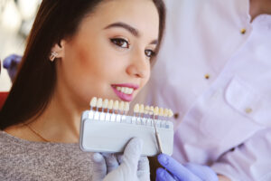 The dentist selects a shade of tooth enamel using a special scale of the table