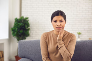 Dental problem concept. Portrait of young woman with acute toothache, inflamed nerve, or cheek swelling after tooth removal. Webcam head shot of sad female patient suffering from severe pain at home